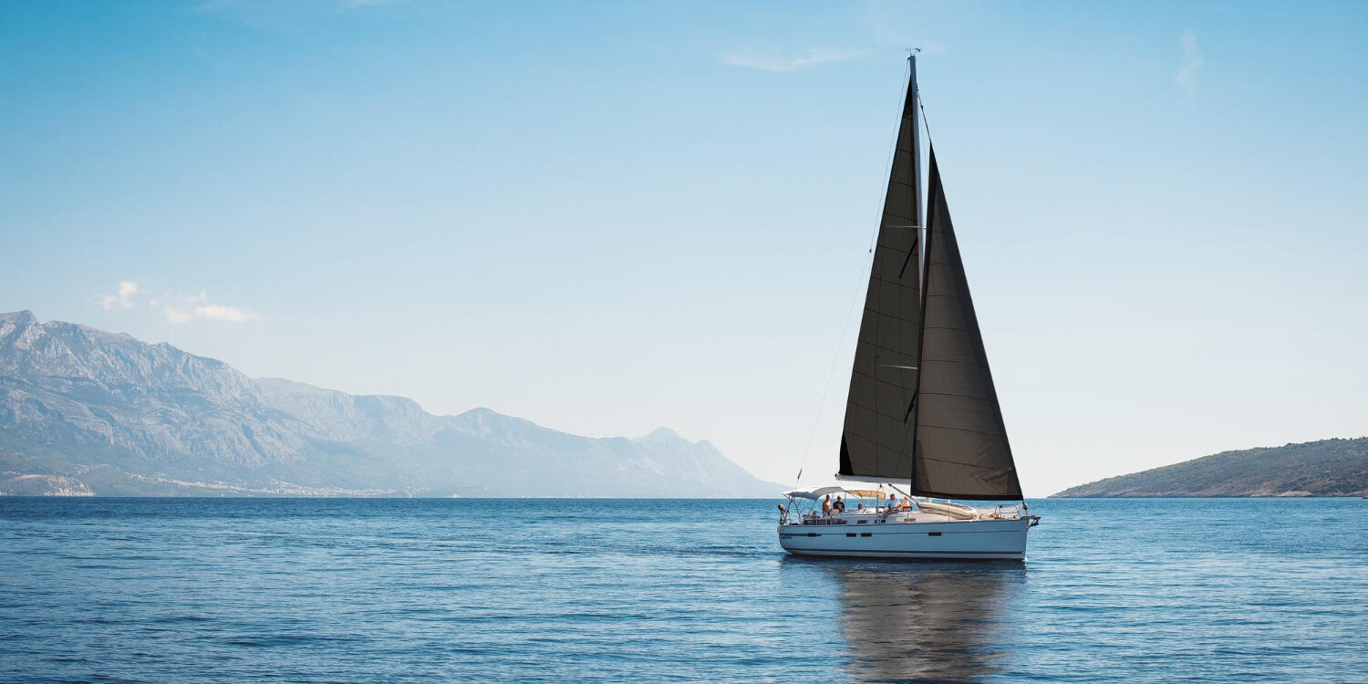 white-yacht-with-black-sails-sea-against-background-blue-sky-mountains