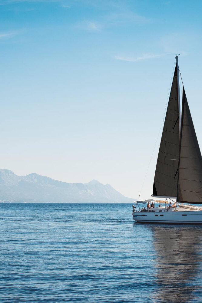 white-yacht-with-black-sails-sea-against-background-blue-sky-mountains