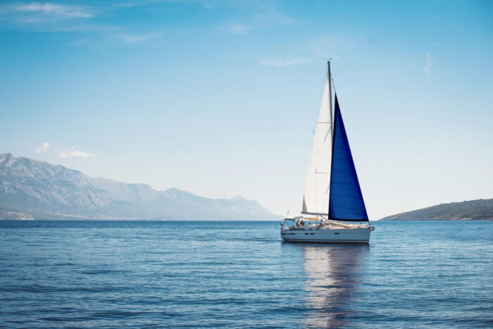 white-yacht-with-blue-white-sails-sea-against-background-blue-sky-mountains