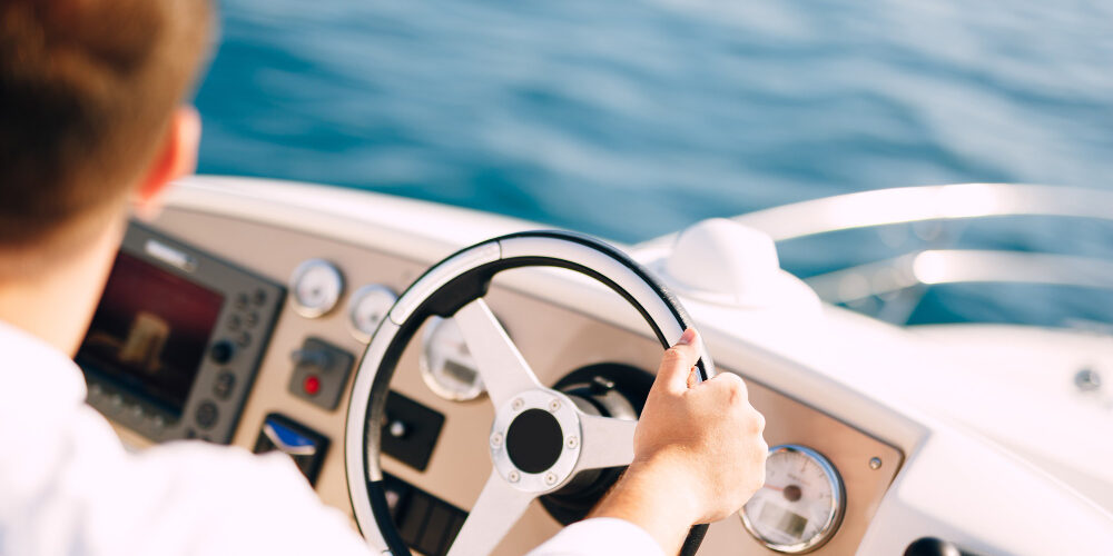 Patente nautica all’estero un uomo che guida una barca dopo aver conseguito la patente nautica all'estero