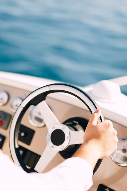 Patente nautica all’estero un uomo che guida una barca dopo aver conseguito la patente nautica all'estero